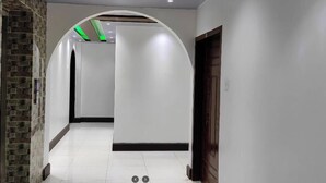 A hallway with white walls, a stone accent wall, a wooden door, and green lighting.
