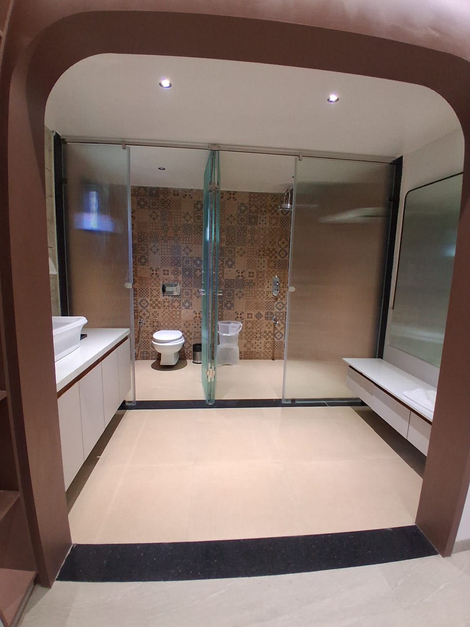 A modern bathroom with a glass shower enclosure, a toilet, and a sink.