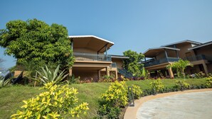 A hotel with multiple buildings, balconies, and a landscaped garden with various plants. - Madhuvan Resort (Talala)
