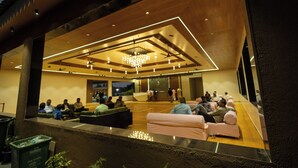 A modern lounge area with seating and a central chandelier. - Madhuvan Resort (Talala)