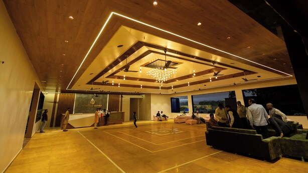 A spacious lobby with a high ceiling, a chandelier, and a reception desk. - Madhuvan Resort (Talala)