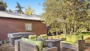 An outdoor patio area with wicker furniture, a hot tub, and a barbecue grill. - Buckthorn Beauty: Private Hot Tub & Lounge Space (Pine Valley)