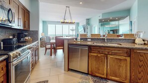 A modern kitchen with granite countertops, stainless steel appliances, wooden cabinets, and a large island with a sink. - 3BR Gulf-Facing Penthouse: Suntide III - Unit 1106 (South Padre Island)