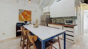 A modern kitchen with white cabinets, a large island with stools, a microwave, a toaster oven, and a hanging light fixture. - Family Friendly! Incline Village Condo w/ Foosball (Incline Village)