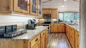 Une cuisine avec des meubles en bois, des plans de travail en granit et une grande fenêtre.