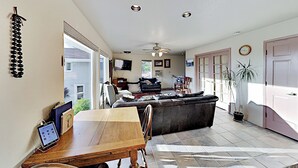 A spacious living area with a dining table, sofa, and ceiling fan.