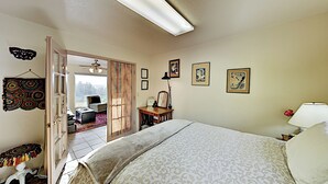 A bedroom with a large bed, a desk, a chair, and a window with a view.