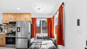 A compact kitchen with modern appliances, a dining area, and a large window with curtains. - Beautiful 1-bedroom bungalow with AC in pleasant Tustin (Tustin)