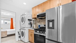 A compact kitchen with stainless steel appliances, including a refrigerator, oven, and washing machine. - Beautiful 1-bedroom bungalow with AC in pleasant Tustin (Tustin)