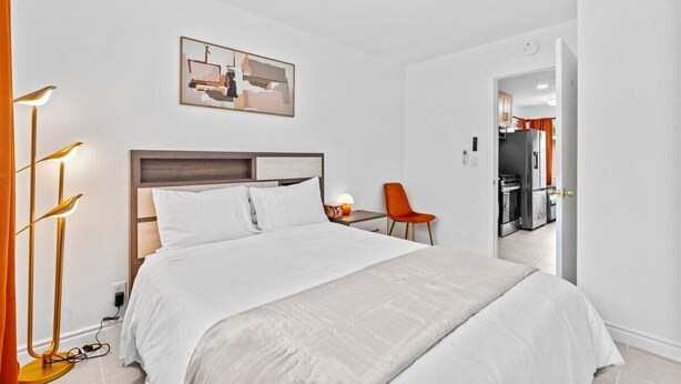 A hotel room with a bed, a desk, a chair, a lamp, and a painting on the wall. - Beautiful 1-bedroom bungalow with AC in pleasant Tustin (Tustin)
