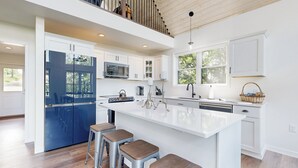 A modern kitchen with a large island, bar stools, and a view of the outdoors. - Hot Tub, River Views! Luxurious Wisconsin Retreat (Eastman)