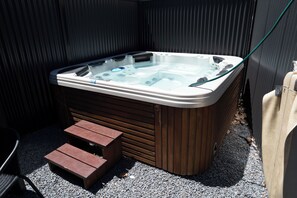 A hot tub with a wooden exterior, a glass top, and a hose attached. There are steps leading up to the tub and a chair to the side. - 1890s Sandstone Villa in Heart of Adelaide (Kent Town)