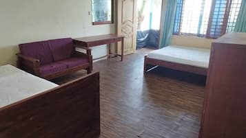 A room with a wooden floor, a purple sofa, a wooden bed, a wooden desk, and a wardrobe.