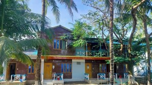 A two-story building with a covered porch and a fenced courtyard. - Shimana Periye Resort SaintMartin Island (Saint Martin's Island)