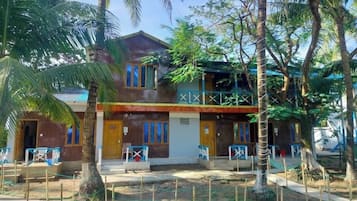 A two-story building with a covered porch and a fenced courtyard.