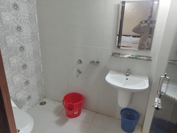 A small bathroom with a white sink, a mirror above it, and a red bucket on the floor. - Shimana Periye Resort SaintMartin Island (Saint Martin's Island)