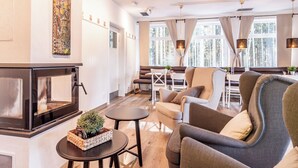 Una sala de estar moderna con chimenea, asientos cómodos y grandes ventanales con vistas al exterior.