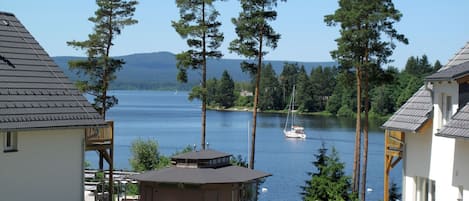 A lakeside property with a cabin, a gazebo, and a view of the lake and sailboat.
