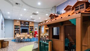 A children's play area with a wooden playhouse, tables, chairs, and a bookshelf filled with books. - 2-bedroom hotel suites walking distance to Heavenly Gondola (South Lake Tahoe)