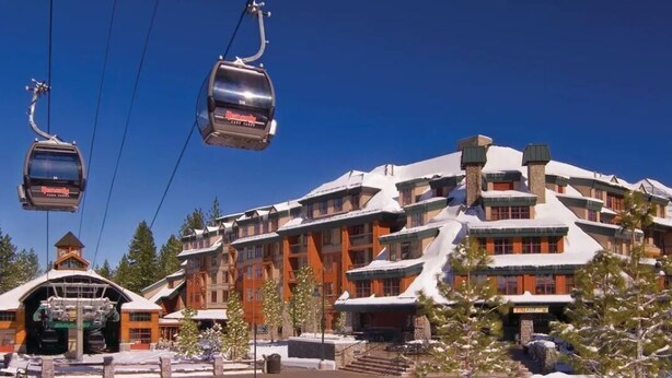 A ski resort with a large building featuring multiple balconies and a ski lift in operation. - 2-bedroom hotel suites walking distance to Heavenly Gondola (South Lake Tahoe)