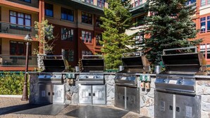 An outdoor grill area with multiple barbecue stations, stone walls, and a paved walkway. - 2-bedroom hotel suites walking distance to Heavenly Gondola (South Lake Tahoe)