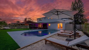 Ein modernes Haus mit Swimmingpool, Liegestühlen im Freien und einer Terrassenanlage.