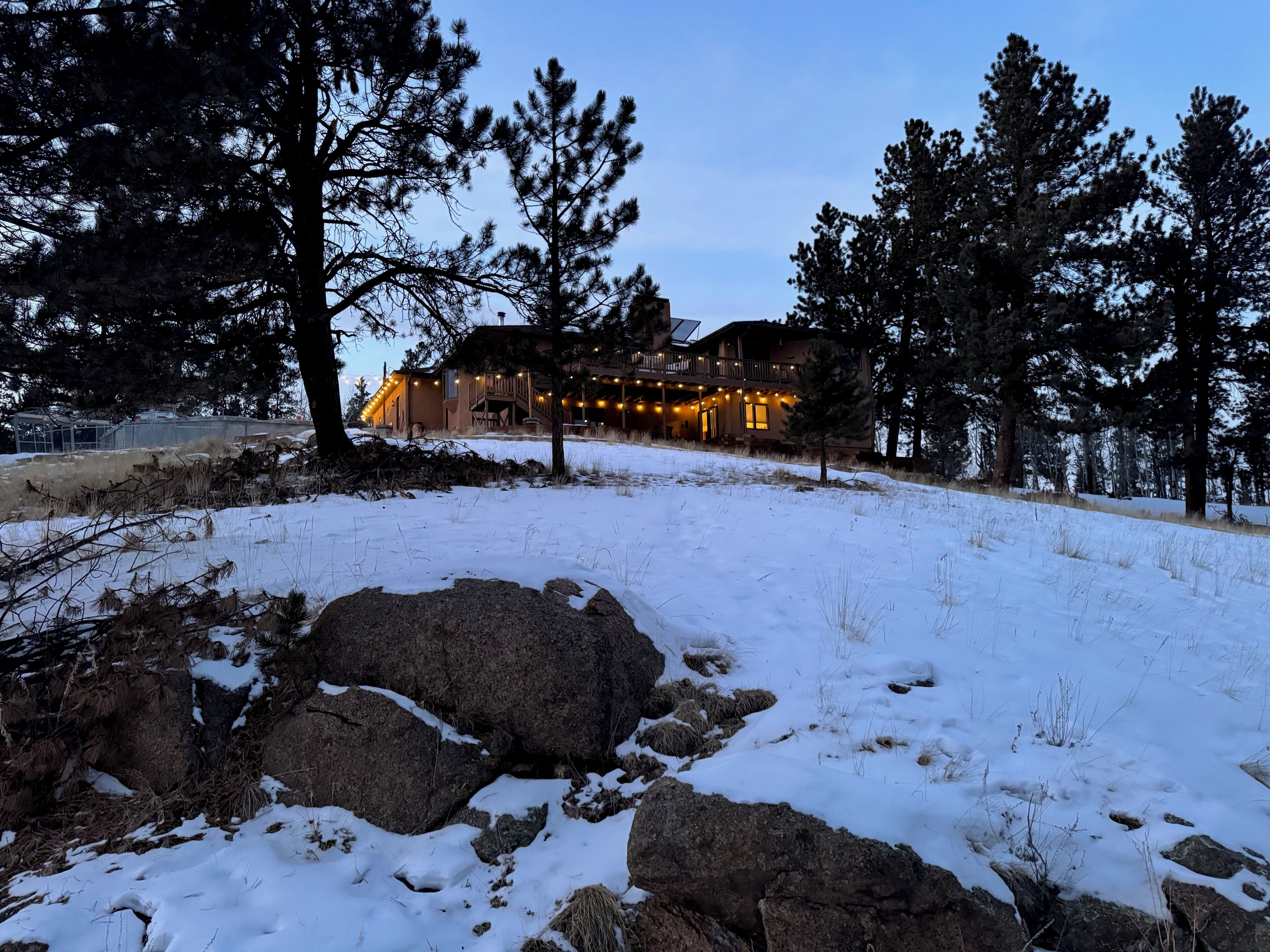 A lodge with a large stone entrance, surrounded by snow-covered ground and pine trees.