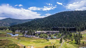 A golf course with a clubhouse, surrounded by forested hills. - 7th-Floor Everline Suite w/ Winter Resort Perks! (Olympic Valley)