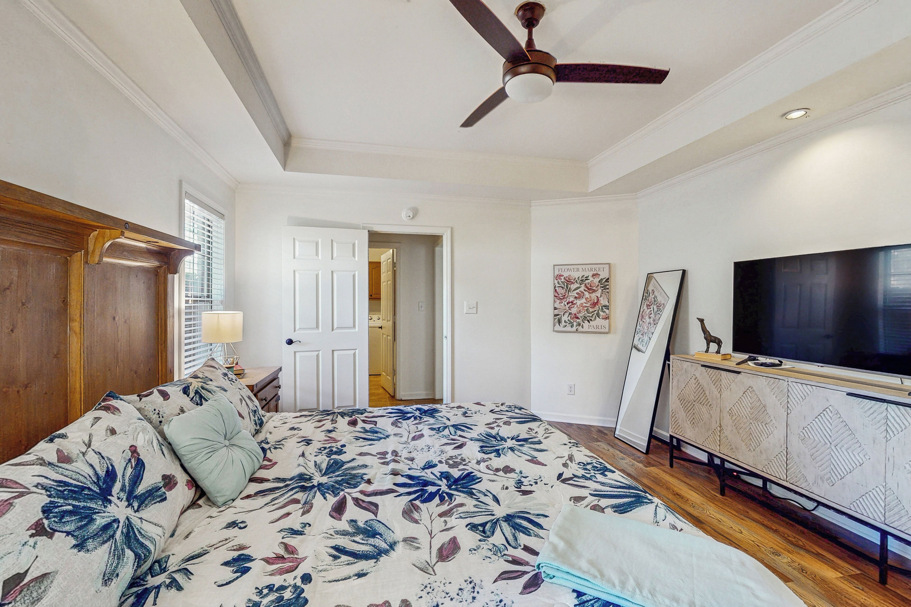 A bedroom with a bed, a ceiling fan, a TV, and a cabinet.