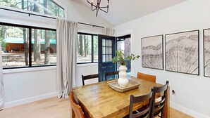 A dining area with a wooden table, chairs, a chandelier, and artwork on the walls. - Hot Tub & Game Room! Pinetop 'Wild Horse Retreat' (Pinetop)