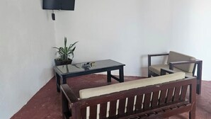 A room with a wooden bench, a small table, a chair, a potted plant, and a mounted television. - Casa Sol Managua: Your Warm and Familiar Refuge in Villa Sol (Managua)