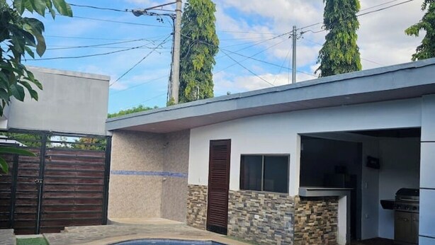 A modern house with a swimming pool, stone wall, and a barbecue area. - Casa Sol Managua: Your Warm and Familiar Refuge in Villa Sol (Managua)