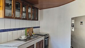 A kitchen with wooden cabinets, a stainless steel refrigerator, and a tiled backsplash. - Casa Sol Managua: Your Warm and Familiar Refuge in Villa Sol (Managua)