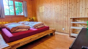 Una habitación tipo cabaña de madera con una cama, un escritorio y una ventana con cortinas.