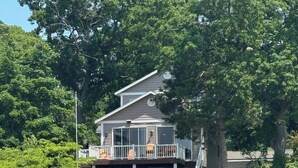 A house with a deck and stairs leading to a dock. - Eagles Landing - Lakefront Home on crystal clear Wolf Lake (Muskegon)
