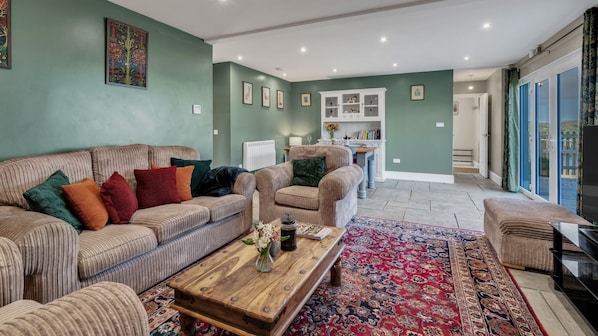 A spacious living room with a striped sofa set, a wooden coffee table, and a patterned rug.