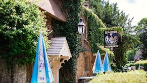 A building with ivy-covered walls, a sign reading "Falkland Arms WADWORTH," and blue umbrellas. - Oak Cottage - Pet friendly, Swerford (Swerford)