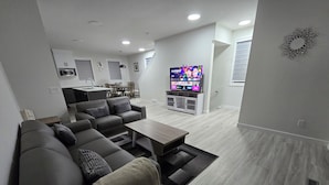Un soggiorno moderno con un divano componibile, un tavolino e una TV sullo sfondo.