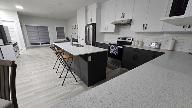 Una cucina moderna con isola centrale, elettrodomestici in acciaio inossidabile e pavimento grigio screziato.