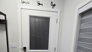 Una porta bianca con una griglia di aerazione, un tappetino nero e un muro con la scritta 'Love You Bye'.