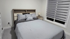Una camera da letto con un letto, comodino, lampada e finestra con persiane.