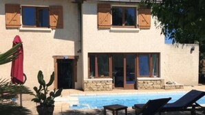 Ein zweistöckiges Gebäude mit Schwimmbecken, Holzfensterläden und einem roten Ziegeldach.