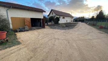 Une propriété située en zone rurale, avec une allée en gravier menant à un bâtiment blanc doté d’un garage.