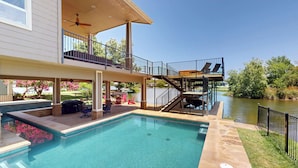 A swimming pool with a covered deck, outdoor seating, and a view of a river. - Luxurious Retreat on Lake LBJ: Pool, Hot Tub, Dock (Granite Shoals)