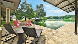 An outdoor patio with stone flooring, wicker chairs, and a table. - Luxurious Retreat on Lake LBJ: Pool, Hot Tub, Dock (Granite Shoals)