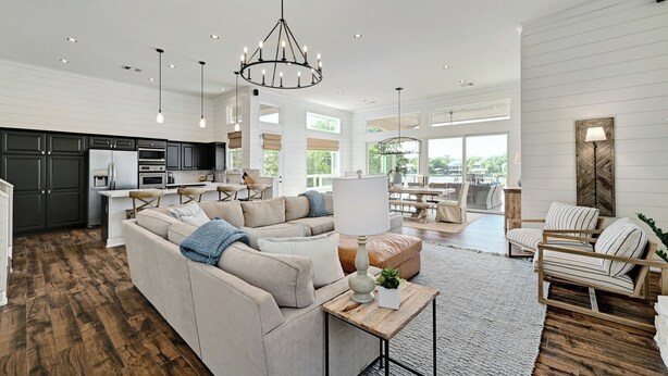 A spacious living room with a sectional sofa, a coffee table, and a chandelier. - Luxurious Retreat on Lake LBJ: Pool, Hot Tub, Dock (Granite Shoals)