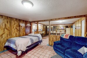 Un dormitorio con una cama, un sofá azul y una kitchenette al fondo.
