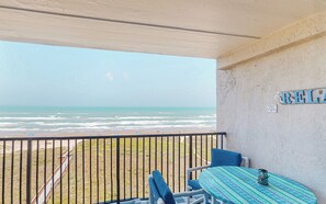 A balcony with a view of the beach, a table with a patterned tablecloth, and a sign on the wall. - Coastal 2BR, Steps to Gulf: Suntide III - Unit 709 (South Padre Island)