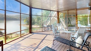 Une vaste terrasse offrant une vue sur un lac et des montagnes, aménagée avec des chaises et une table.
