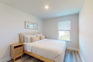 A bedroom with a bed, nightstand, and a window with blinds. - Steps to Sand & Surf! Family-Friendly PCB Retreat (Panama City Beach)